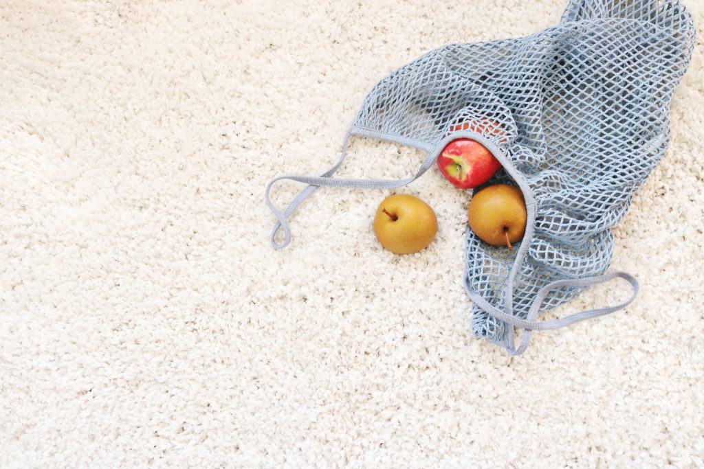 A bag of apples casually placed on a new cream coloured carpet